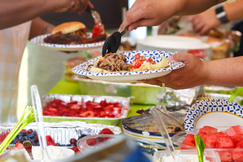 Person serving themselves food at a summer picnic.