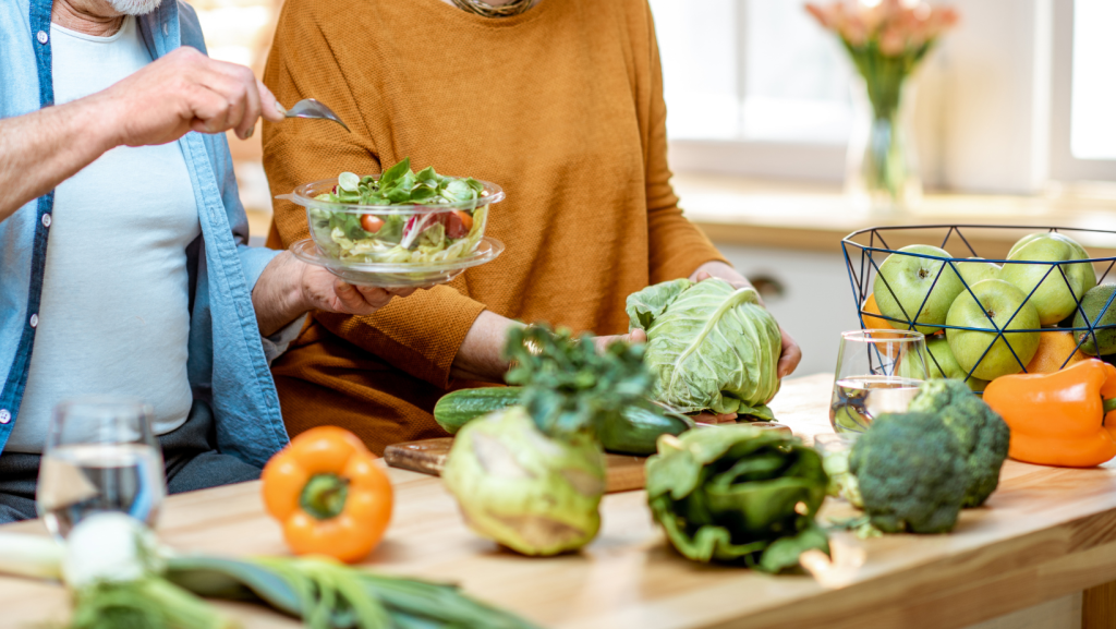 Older couple preparing fresh vegetables as part of a healthy lifestyle to support healthy aging.